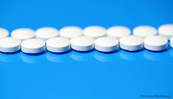 En rad med vita tabletter på blå bakgrund.